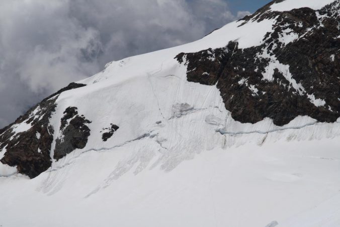 Tři sebevrazi sestupují odpoledním rozměklým sněhem lavinózním svahem z Lyskammu.